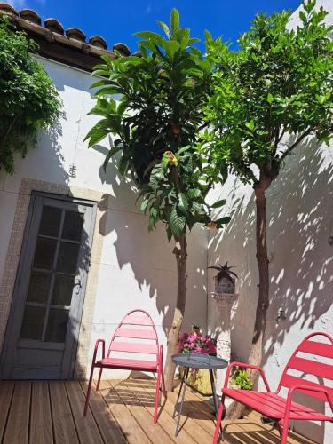une terrasse avec 2 chaises, une table et un arbre dans l'établissement Maison typique intra-muros, à Aigues-Mortes