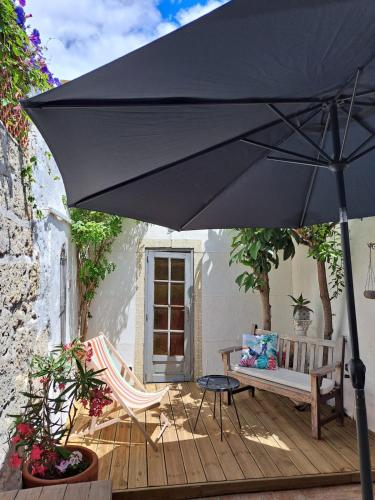 un parasol noir sur une terrasse en bois avec un banc dans l'établissement Maison typique intra-muros, à Aigues-Mortes
