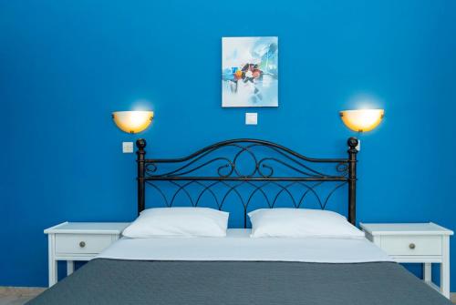 a blue bedroom with a black bed with two lamps at Daphne Bungalows in Tolo