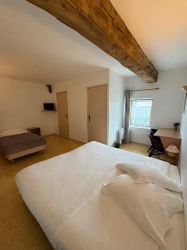 une chambre avec un grand lit blanc et un bureau dans l'établissement Hôtel de l Héritage, à Crannes-en-Champagne