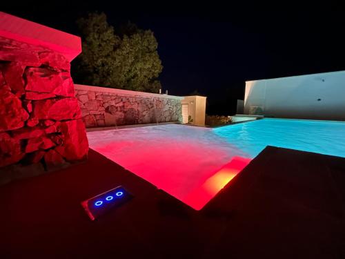 a swimming pool lit up at night with red lights at Abate Filippo apartment in Nardò