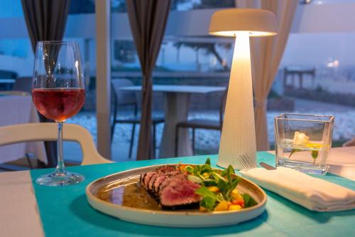 a plate of food on a table with a glass of wine at Isola di Albarella Golf Hotel in Isola Albarella