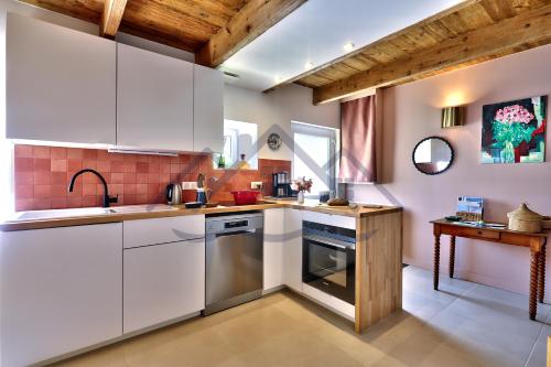 a kitchen with white cabinets and a sink at LocaLise - M6B - Ty pompon, - Maison de vacances dans le centre du Guilvinec - extérieur clos - wifi inclus - animaux bienvenus - à deux pas des plages et du port du Guilvinec in Le Guilvinec