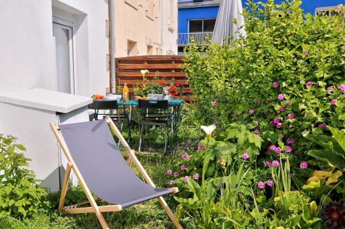 a chair and a table in a garden with flowers at LocaLise - M6B - Ty pompon, - Maison de vacances dans le centre du Guilvinec - extérieur clos - wifi inclus - animaux bienvenus - à deux pas des plages et du port du Guilvinec in Le Guilvinec