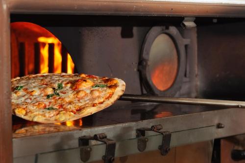 a pizza is being cooked in an oven at Isola di Albarella Golf Hotel in Isola Albarella