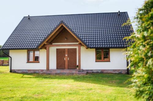 a white house with a black roof at Domek całoroczny na Kaszubach II Bliźniak in Lipusz
