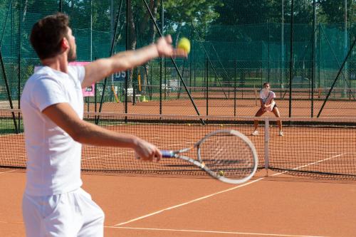 a man hitting a tennis ball with a racket at Isola di Albarella Golf Hotel in Isola Albarella