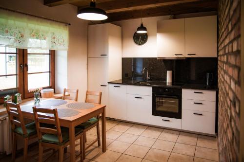 a kitchen with white cabinets and a table and chairs at Domek całoroczny na Kaszubach II Bliźniak in Lipusz