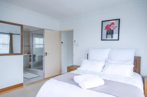 a white bed with white pillows in a bedroom at Vredekloof Views in Cape Town