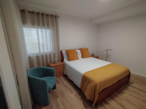 a bedroom with a bed and a chair and a window at Casa da TITA in Vila Praia de Âncora