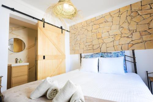 a bedroom with a large bed with a stone wall at Casinha da Raposeira in Raposeira