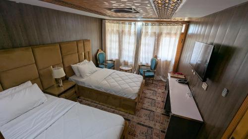 a hotel room with two beds and a television at The Jade Palace, Hunza in Karimabad Hunza