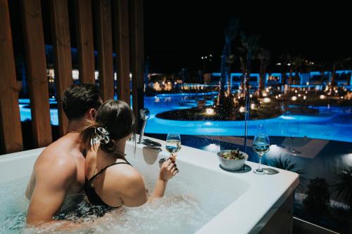 a man and a woman in a bath tub with wine glasses at Anna Island in Pefkohori