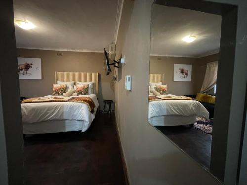 a bedroom with two beds and a mirror at Homely Home Guest House in Roodepoort