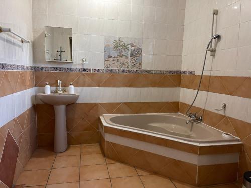 a bathroom with a tub and a sink at Homely Home Guest House in Roodepoort