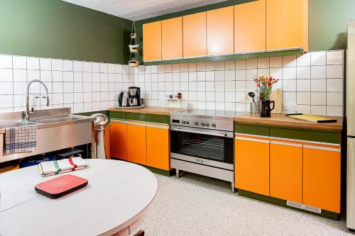 a kitchen with orange cabinets and a table at C'est Chouette le gîte ! in Saint-Jodard