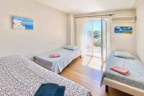 une chambre avec deux lits et un balcon dans l'établissement Les jasmins piscine proche mer jardin, à Saint-Raphaël