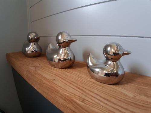 three metal birds sitting on a wooden shelf at All Manor Of Events - Glamping Pods in Henley