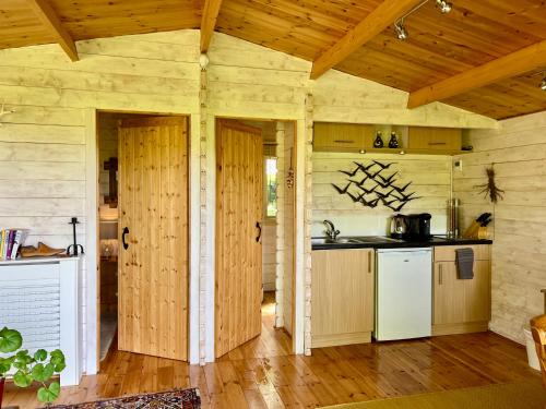 an open kitchen with wooden walls and wooden floors at Tranquil Norfolk Log Cabin - Stunning Rural Sunset Views in Weston Longville