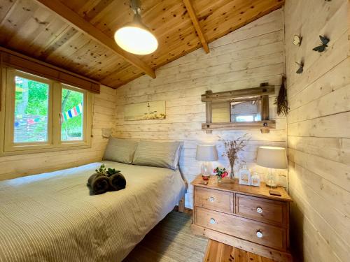 a bedroom with a bed and a wooden wall at Tranquil Norfolk Log Cabin - Stunning Rural Sunset Views in Weston Longville