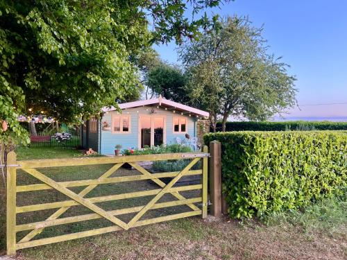 a gate in front of a house with a fence at Tranquil Norfolk Log Cabin - Stunning Rural Sunset Views in Weston Longville