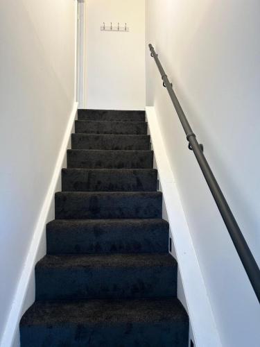 a staircase with blue carpet and white walls at Niamh's Place in Northallerton