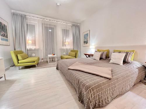 ブレーメンにあるBremen City Apartmentのベッドルーム1室(大型ベッド1台、緑の椅子2脚付)