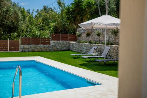 a swimming pool in a yard with chairs and an umbrella at Aristides Cottage in Kassiopi