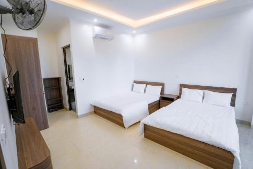 a bedroom with two beds and a flat screen tv at Hiếu Thảo Hotel & Restaurant Sầm Sơn in Sầm Sơn