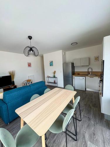un salon avec une table et un canapé bleu dans l'établissement Nid Urbain - 3 Ch et Terrasse, à Saint-Herblain