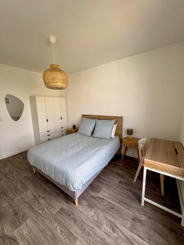 une chambre avec un lit et une table en bois dans l'établissement Nid Urbain - 3 Ch et Terrasse, à Saint-Herblain