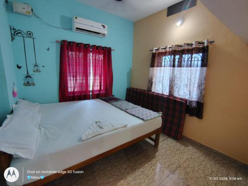 a small bedroom with a bed and red curtains at DSouza Homestay in Māvalli