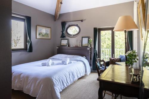 a bedroom with a bed and a table and a clock at La Rose du Petit Bois in Saint-Didier-au-Mont-dʼOr