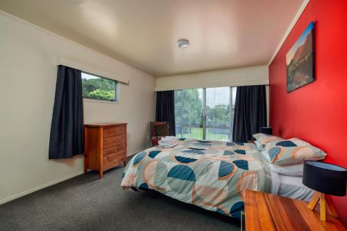 una camera da letto con un letto e una parete rossa di Te Tiriti Beach House - Paihia Holiday Home a Paihia