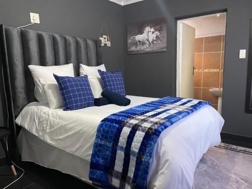a bedroom with a bed with blue and white pillows at Homely Home Guest House in Roodepoort