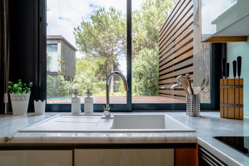 a kitchen with a sink and a large window at Designer Villa in Comporta in Troia