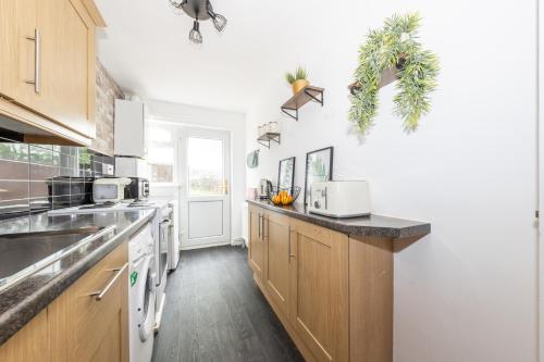 a kitchen with wooden cabinets and a counter top at Executive One Bedroom Maisonette - Garden Access & Free Parking - Prime Location in Luton