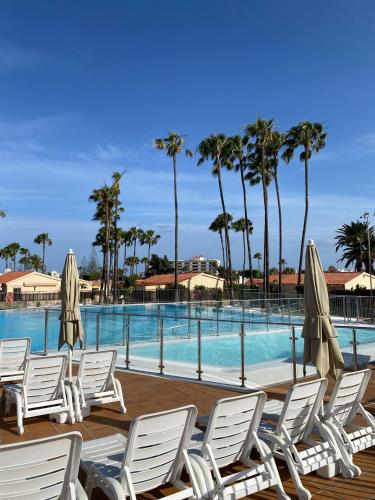 een groep stoelen en parasols naast een zwembad bij Sunny Haven in Santa Fe - Playa del Inglés- Maspalomas in Maspalomas