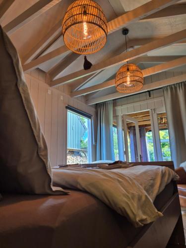 a bedroom with two chandeliers and a bed at Tinyhouse met Hot Tub en ruime privé tuin in Gees