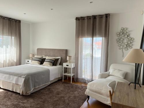 a white bedroom with a bed and a chair at Moradia exclusiva junto ao mar in Gafanha da Nazaré