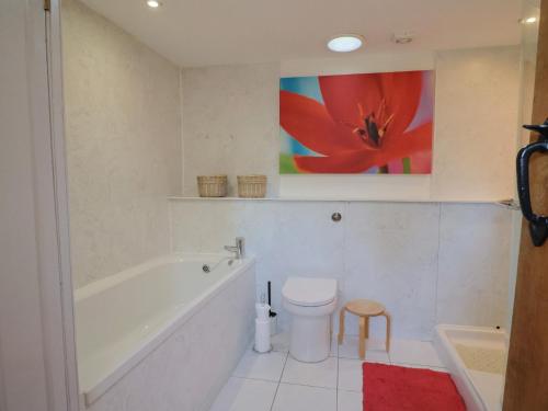 ein Badezimmer mit einer Badewanne, einem WC und einem Gemälde in der Unterkunft Dragon Cottage in Axminster