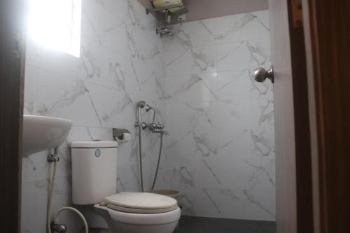 a white bathroom with a toilet and a sink at SHIVANGAN HOTEL and BANQUET in kolkata