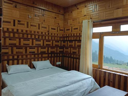 Un dormitorio con una cama y una ventana grande. en Hotel Vishal & Restaurant, en Munsyari