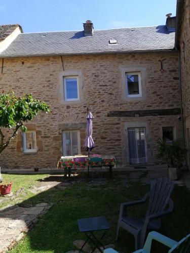 a house with a table and an umbrella in the yard at La Maison des Rosiers in Manhac