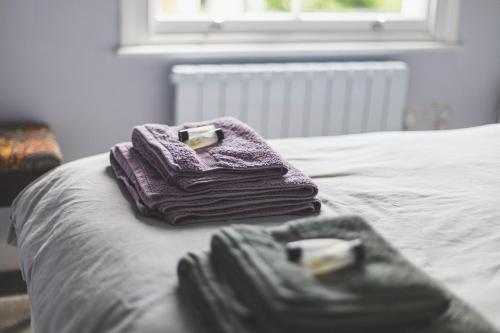 two purple towels sitting on top of a bed at Stylish Flat B in London