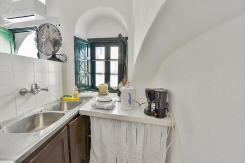 Una pequeña cocina con fregadero y ventana. en Christos Apartments Oia, en Oia