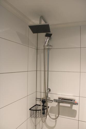 a shower head in a white tiled bathroom at Apartment Gasstorp Wifi in Hova