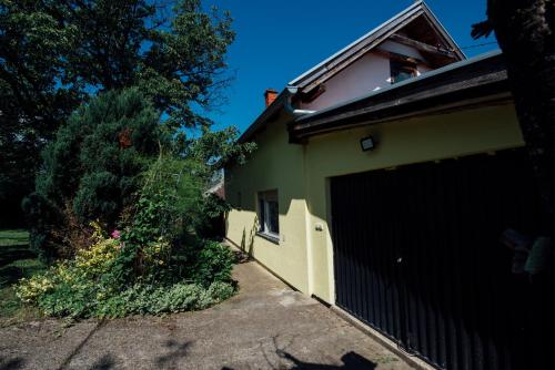 a house with a black gate and a garage at Vikendica Ilic - Petrovac na Mlavi in Porosanica
