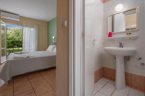 a bathroom with a sink and a bed with a window at Julia Hotel in Fourka