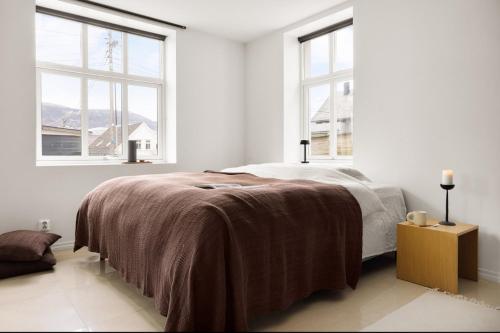 a white bedroom with a bed and two windows at Sentral leilighet, Bergen in Bergen
